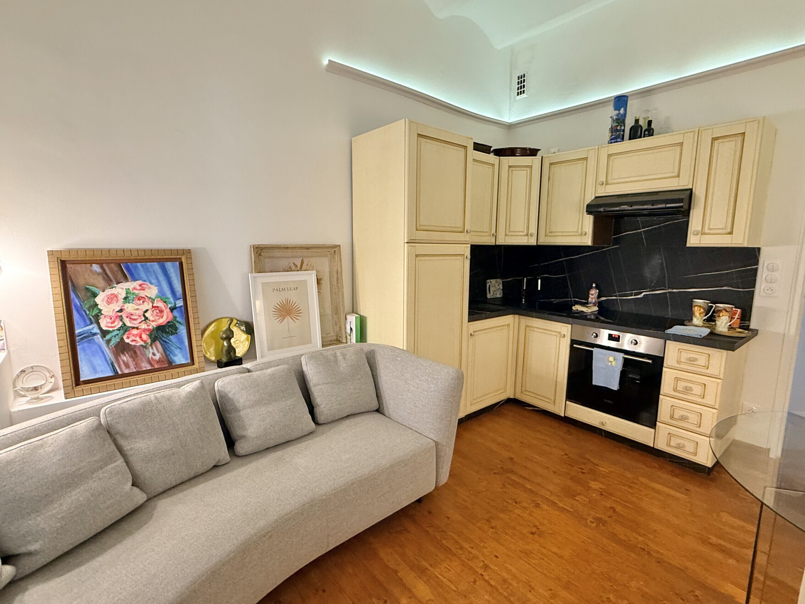 A modern kitchen with light-colored cabinets, a black countertop, and a built-in oven.