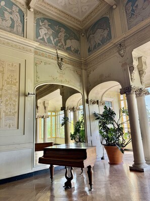 Ein prunkvoller Raum mit klassischer Architektur, darunter Säulen, Bögen und aufwändige Deckenfresken.
