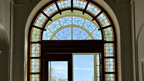 Ein spitzbogiges Portal mit Buntglasfenstern, das in einen Innenhof mit Palmen führt.