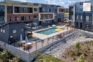 Ein moderner Apartmentkomplex mit Schwimmbad, Sitzgelegenheiten im Freien und einem angelegten Garten.