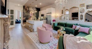 Ein großzügiger Wohnbereich mit moderner Küche, einem grünen Sofa und einer Bar mit Hockern.