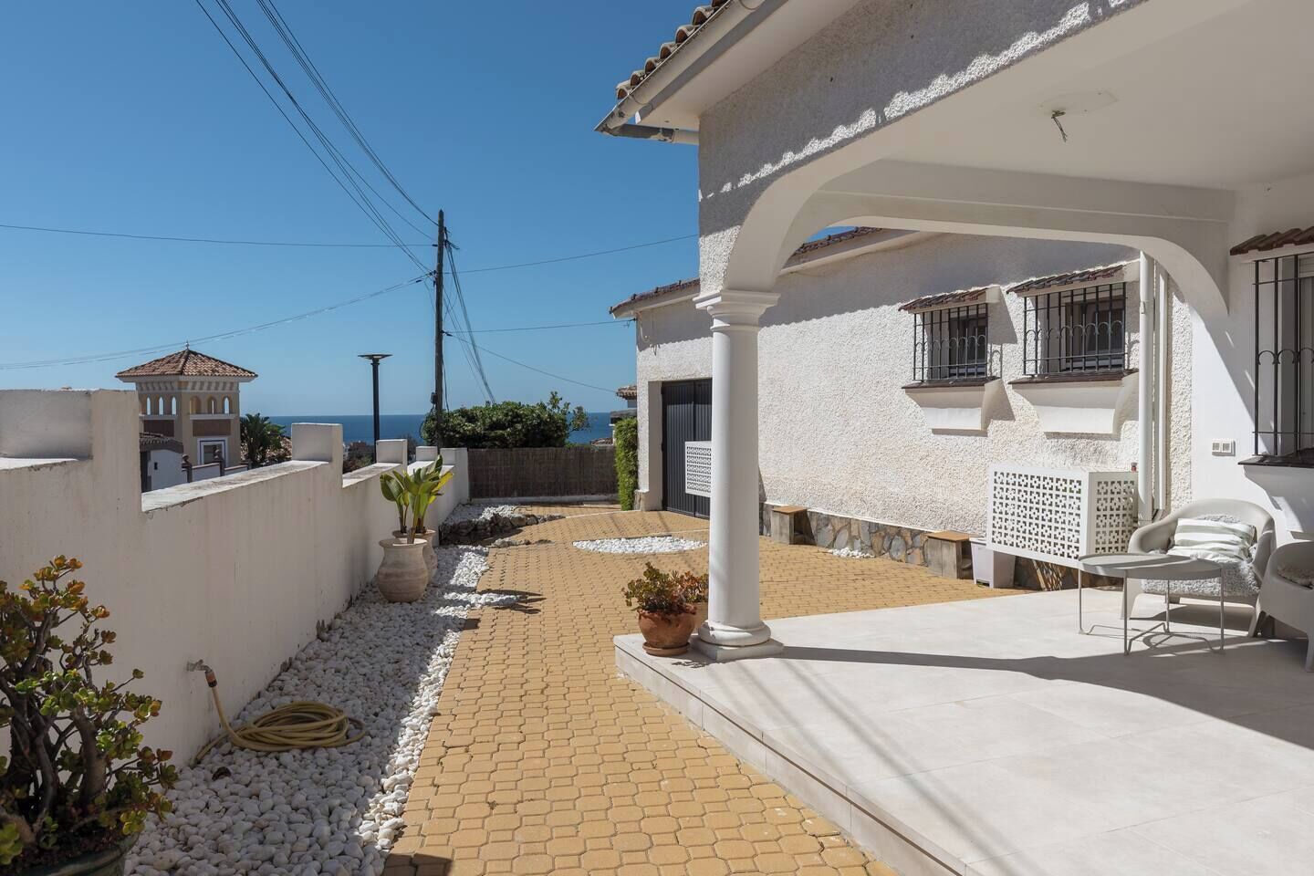 Une propriété résidentielle dotée d’une terrasse dallée, de murs blancs et offrant une vue sur la mer.