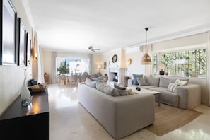 Ein großzügiges Wohnzimmer mit einer großen Couch, einem Essbereich und einem Kamin.