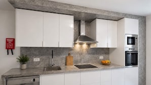 A modern kitchen with white cabinets, a stainless steel range hood, a built-in oven, and a dishwasher. - Luxury Mountain View Apartment in Machico (Machico)