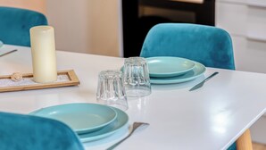 Una mesa de comedor con platos azul turquesa, cristalería transparente y una vela.