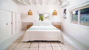 Ein Schlafzimmer mit einem Bett, zwei Nachttischen, einem Fenster mit Blick und einem Deckenventilator.