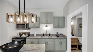 A modern kitchen with a central island, a microwave, a stove, and a hanging light fixture. - The Dugout | Hot Tub (Columbia)