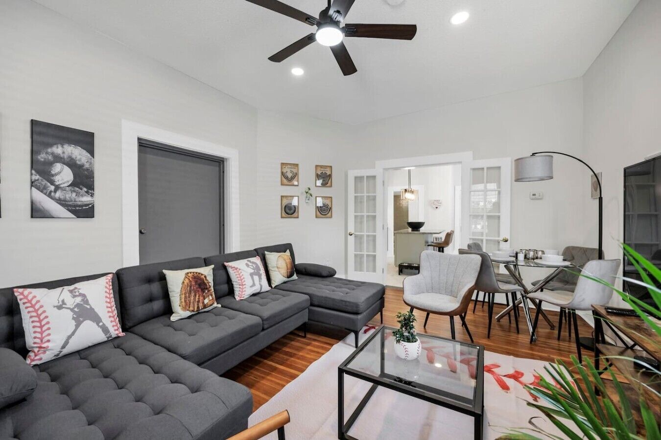 A modern living room with a sectional sofa, a glass coffee table, and a dining area with a table and chairs.
