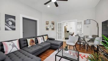A modern living room with a sectional sofa, a glass coffee table, and a dining area with a table and chairs.