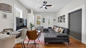 A spacious living room with a large sectional sofa, a dining area, and a ceiling fan. - The Dugout | Hot Tub (Columbia)