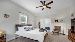 A bedroom with a bed, a ceiling fan, a chair, a desk, a TV, and a wardrobe. - The Scoreboard | Hot Tub (Columbia)