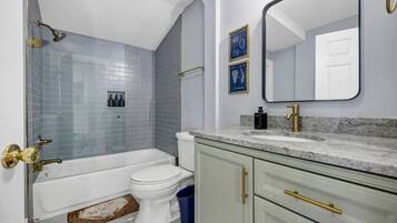 A bathroom with a bathtub, toilet, and vanity with a mirror.