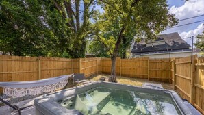 A backyard with a hot tub, a hammock, and a wooden fence. - The Scoreboard | Hot Tub (Columbia)