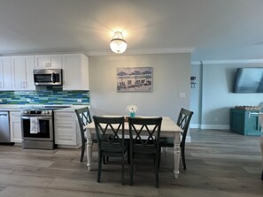 A modern kitchen with white cabinets, a microwave, an oven, and a dining area with a table and chairs.