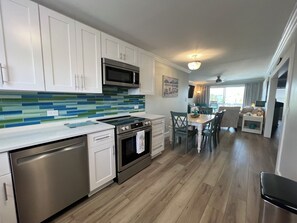 A modern kitchen with white cabinets, a stainless steel dishwasher, and a tiled backsplash.