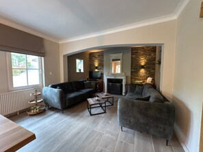 Ein modernes Wohnzimmer mit Kamin, zwei Sofas, einem Couchtisch und einem Fernseher.