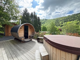 Una sauna de madera con puerta, un jacuzzi y una terraza.