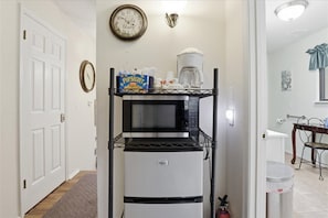 Eine kleine Küche mit Mikrowelle, Kaffeemaschine und Kühlschrank.