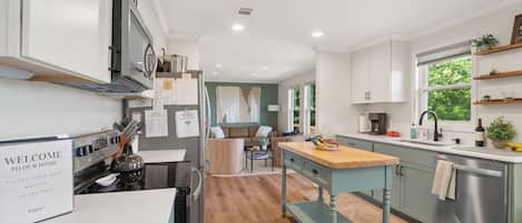 A modern kitchen with a central island, built-in appliances, and a view into the living area.
