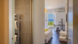 Ein Hotelzimmer mit Bett, Schreibtisch, Stuhl und Meerblick.
