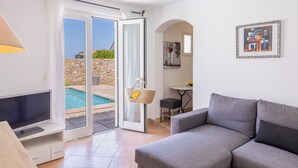 Ett vardagsrum med en grå soffa, en tv och en pool utomhus.
