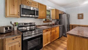 A kitchen with wooden cabinets, stainless steel appliances, and a granite countertop. - 4 Bears Lodge at Edgewater - Entire Lodge 6 Rooms (Forsyth)