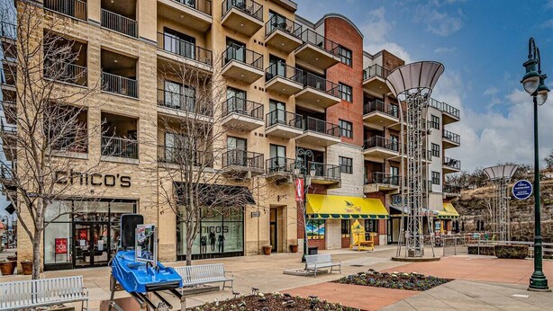 A multi-story building with balconies, a patio area with benches, and a storefront with a yellow awning. - 4 Bears Lodge at Edgewater - Entire Lodge 6 Rooms (Forsyth)