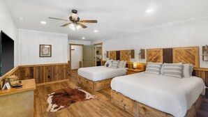A room with two beds, a ceiling fan, wooden walls, a cowhide rug, and a framed picture on the wall. - 4 Bears Lodge at Edgewater - Entire Lodge 6 Rooms (Forsyth)