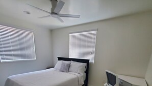 Un dormitorio con cama, escritorio y ventilador de techo.