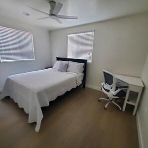 Ein Schlafzimmer mit einem Bett, einem Schreibtisch und einem Deckenventilator.