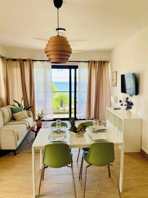 A modern living room with a dining area, large windows, a flat-screen TV, and a view of the outdoors. - Perfect Place in Samana 1 (Samaná)