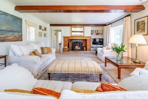 Ein Wohnzimmer mit Kamin, Sofas, einem Couchtisch und einem Gemälde an der Wand.