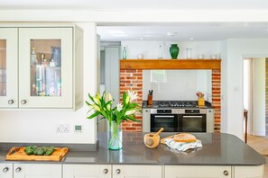 Eine Küche mit Backsteinwand, Holz Arbeitsplatte, einer Vase mit Blumen und einem Schneidebrett mit Avocados.
