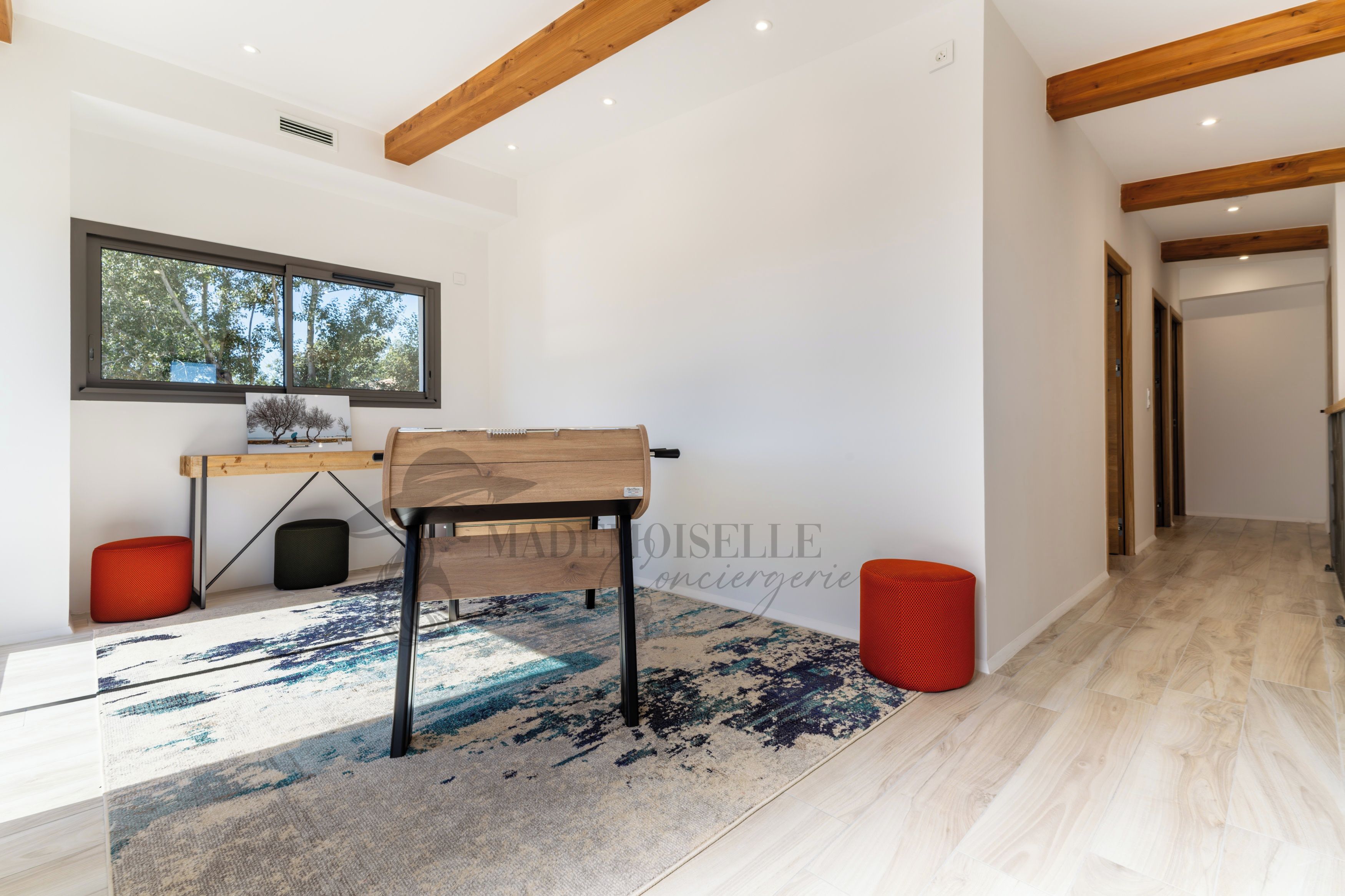 A modern interior with a wooden desk, a large window, and a patterned rug.