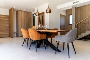 Ein stilvoller Essbereich mit einem Holztisch, vier Stühlen und zwei Pendelleuchten.