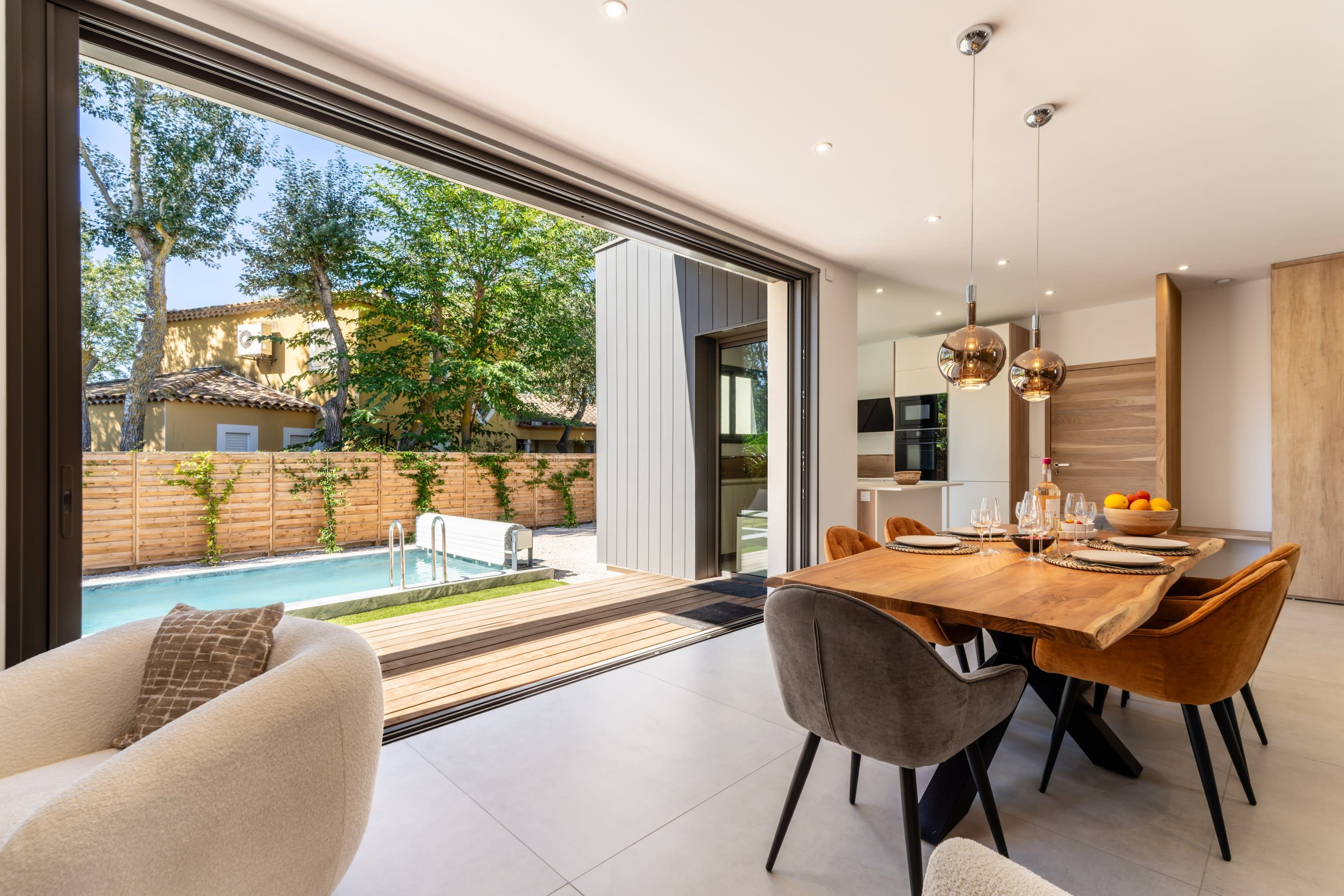 A modern dining area with a pool view, a wooden dining table, and contemporary chairs.