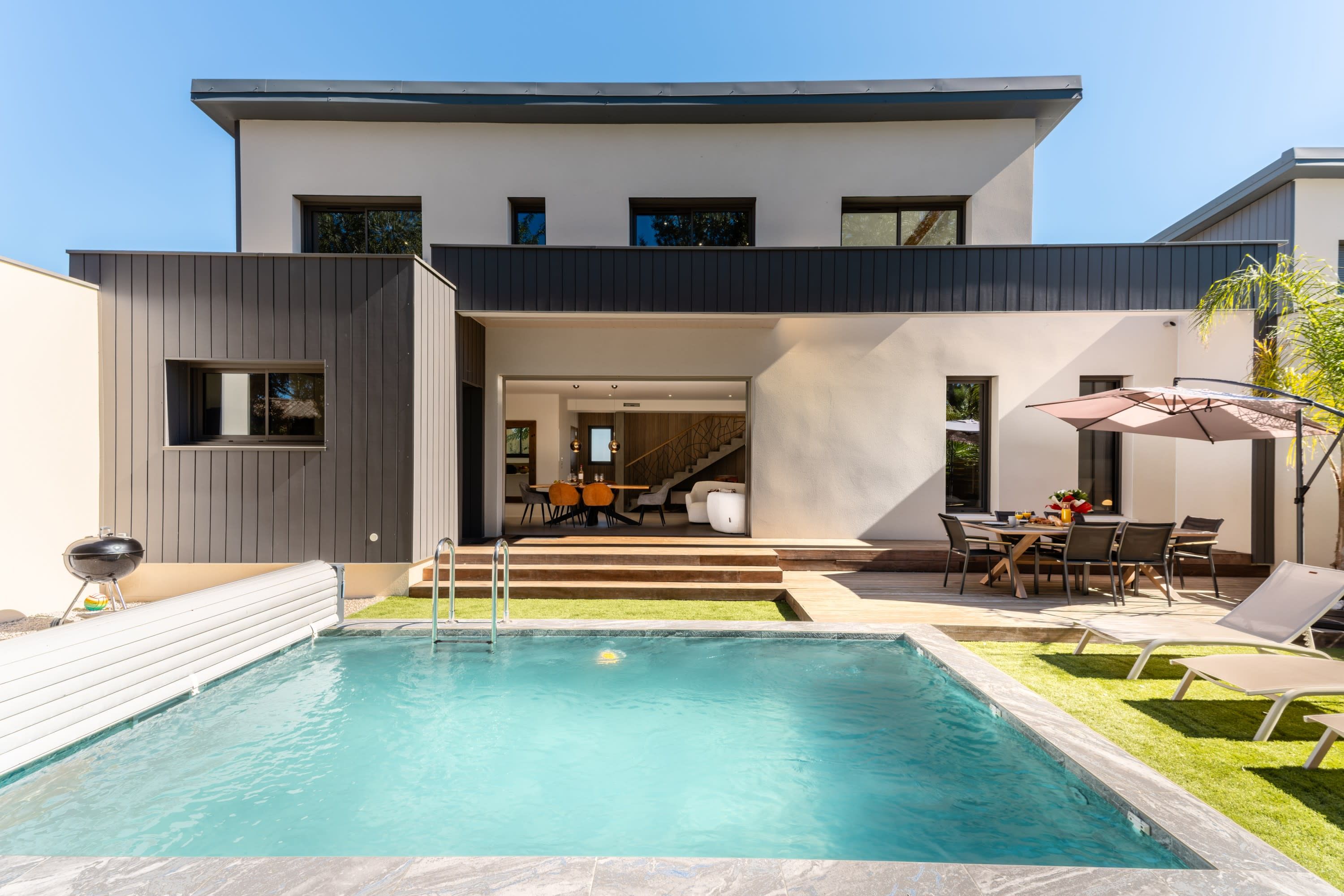 Une maison moderne à deux étages, dotée d’une piscine, d ’un espace salon extérieur et d’un escalier menant à un niveau supérieur.
