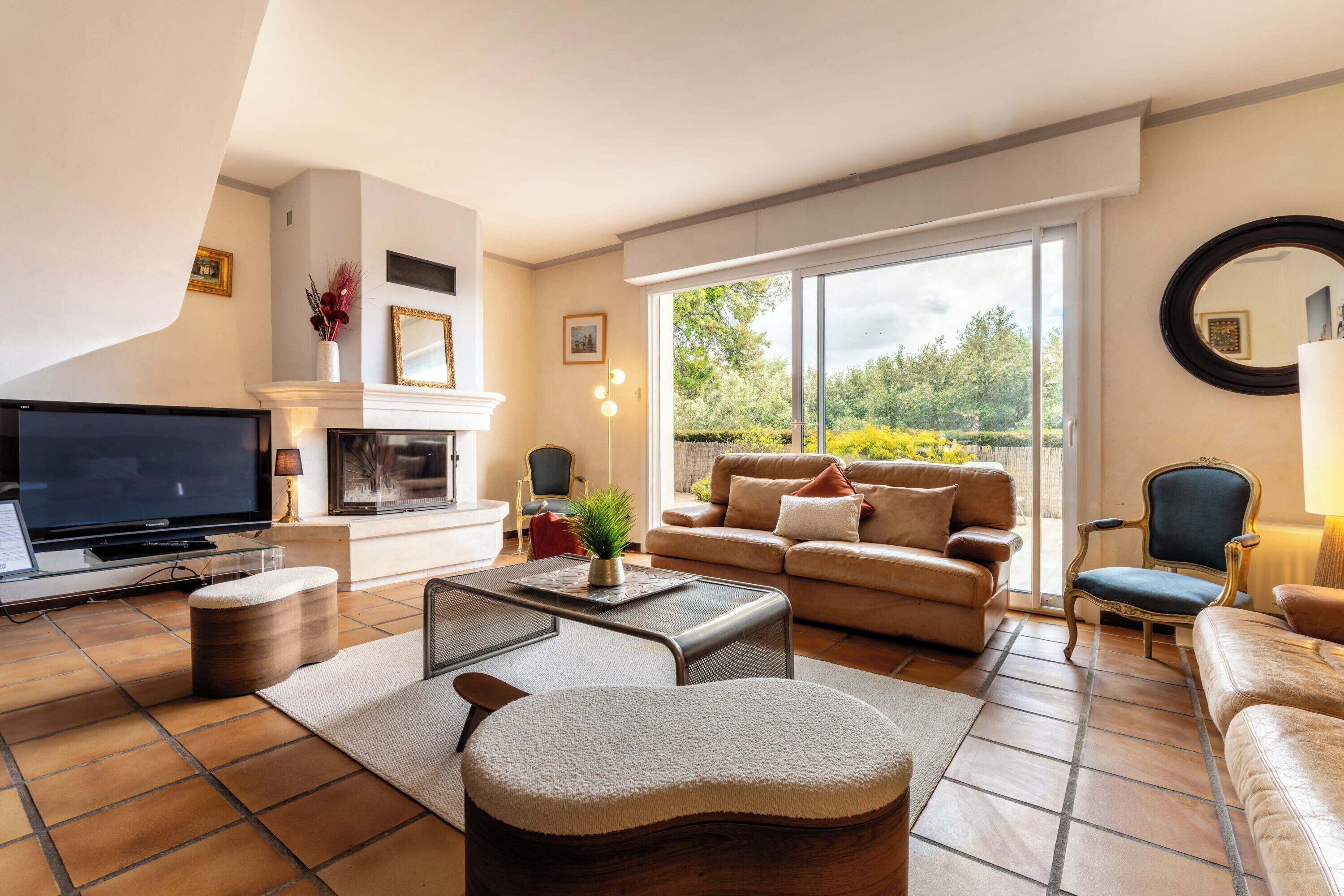 Een woonkamer met een televisie, bank, fauteuils en een open haard.