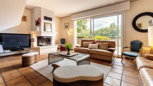 A living room with a TV, sofa, armchairs, and a fireplace.