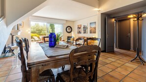 A dining area with a long wooden table, chairs, and a blue vase.