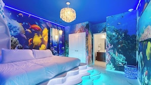 Ein Schlafzimmer mit einem Bett, einer Kristallleuchtre und Wänden, die Unterwasserwelten zeigen.