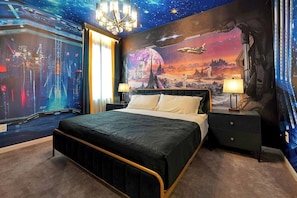 Ein Schlafzimmer mit einem großen Bett, einem Nachttisch, einer Lampe und einem Wandgemälde mit Weltraummotiven.