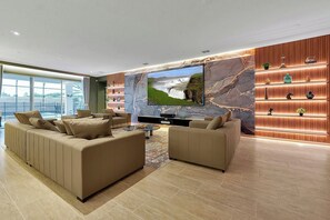 Ein modernes Wohnzimmer mit einem großen Flachbildfernseher, zwei Sofas, einem Couchtisch und einer Marmorwand.