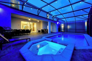 Ein Innenpool mit Glasdach, ein Barbereich und eine Sitzgruppe mit Tischen und Stühlen.