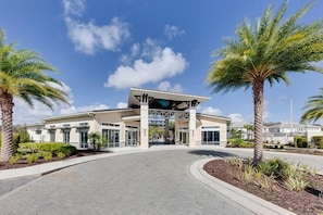 A hotel entrance with a covered walkway, palm trees, and a clear sky. - Luxury Lake Views 15BR 16.5BA, Sleeps 40, Theater (Kissimmee)
