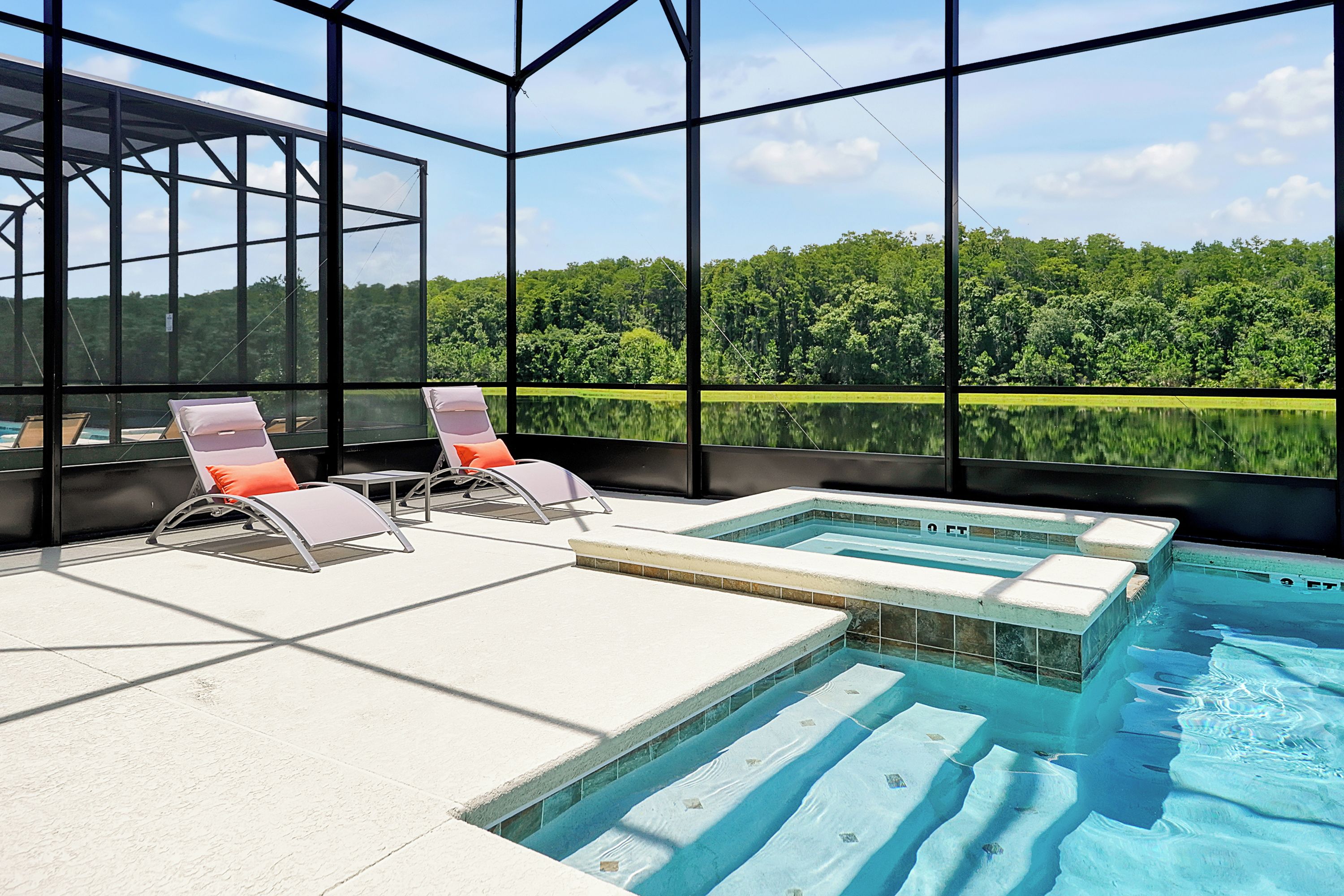Ein Poolbereich mit zwei Liegestühlen und Blick auf einen Wald.