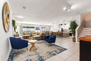 Ein großzügiger Wohnbereich mit einer Couch, Sesseln, einem Couchtisch und einer Küche im Hintergrund.