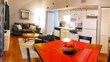 A compact living space with a dining area, kitchenette, and a sofa in the living room.