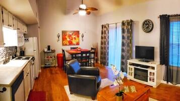 A compact living space with a kitchenette, dining area, seating, and a TV.