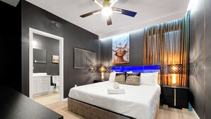 Een moderne slaapkamer met een bed, nachtlampjes, een plafondventilator en een groot raam met gordijnen.